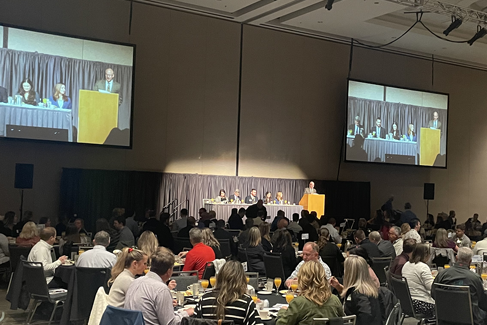 Conference room with a speaker at the podium, large audience watching.