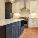 Modern kitchen with marble island and wooden floors.