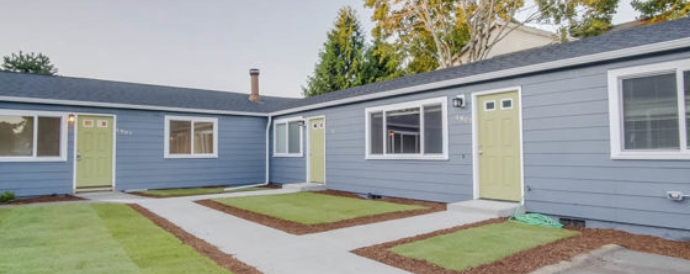 Single-story blue duplex with light green doors and a shared courtyard.